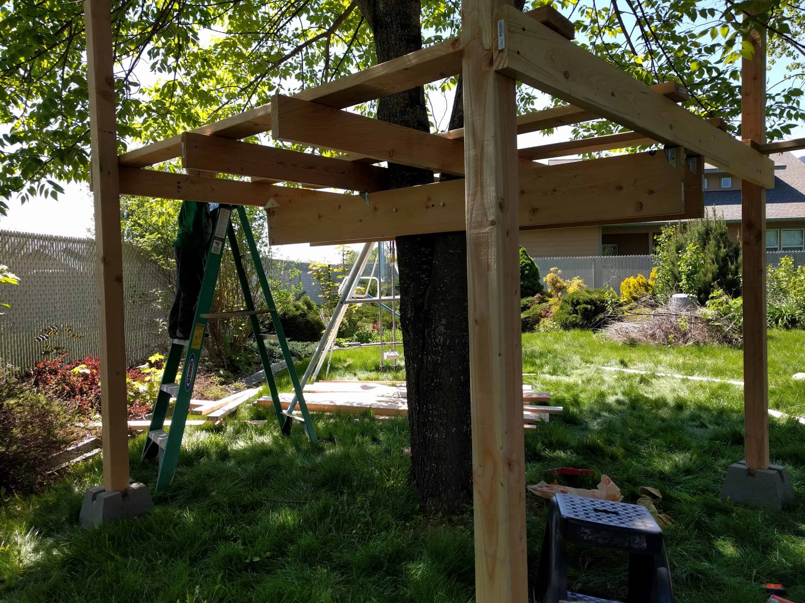 Framing of treefort. Beams, joists, and vertical posts attached at each corner.