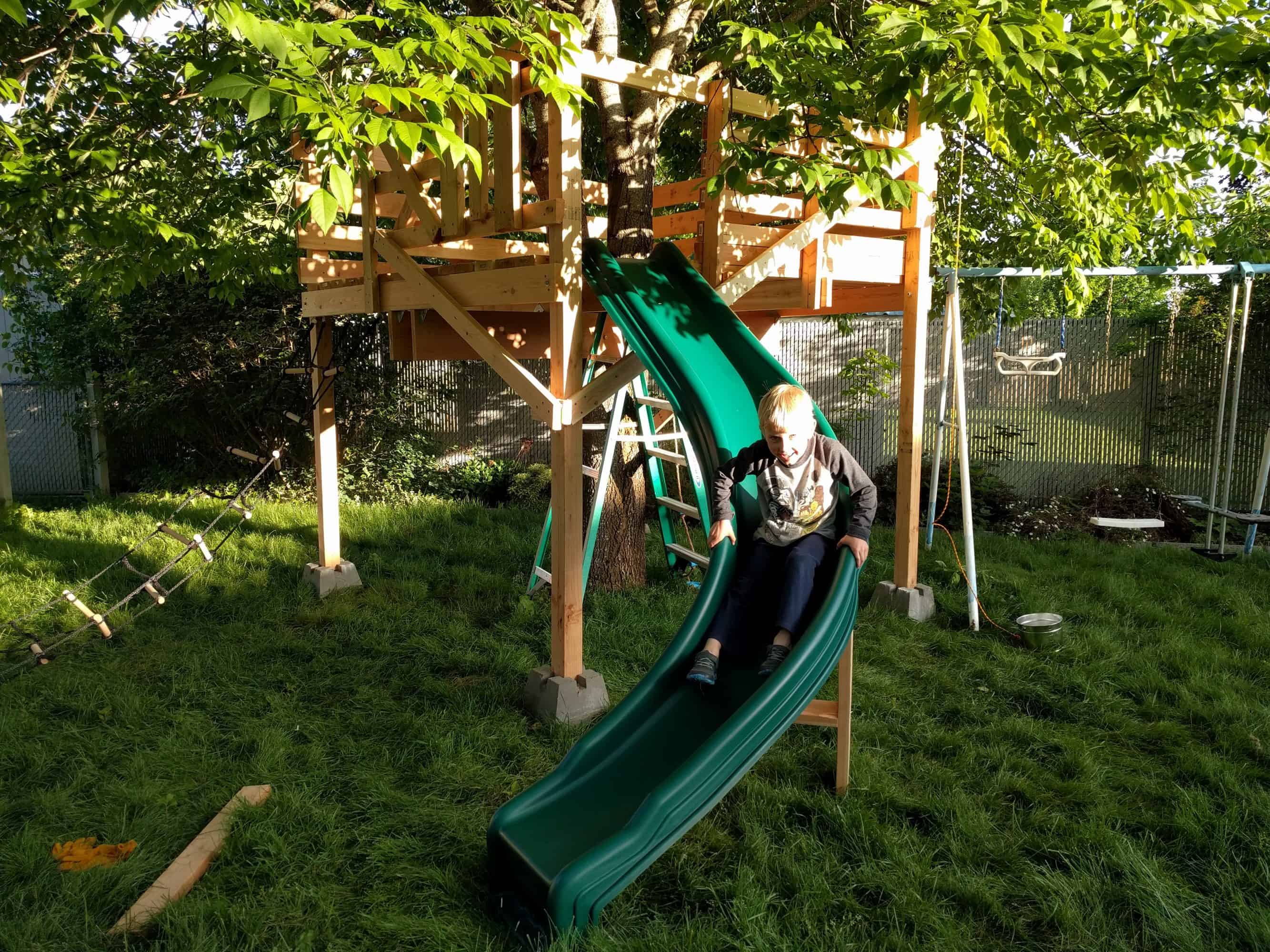 Slide is attached to teehouse. Eli is going down slide.