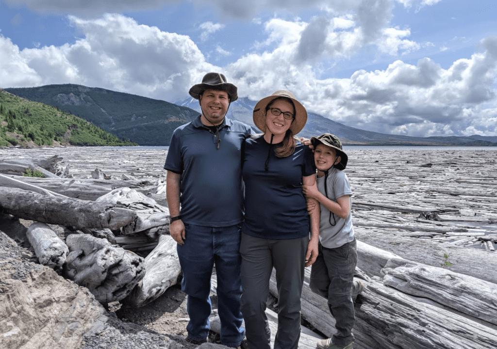 Family in front of floating logs on Spirit Lake